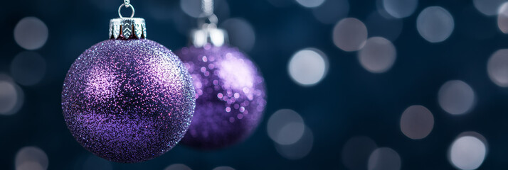 Poster - Glittering purple and silver Christmas balls suspended in midair with a magical snowy out of focus background 