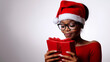 © MonkaLemonka - portrait of middle aged african american christmas woman in red santa hat with gift box; white background; copy space
