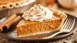 © YanabY - Delicious slice of pumpkin pie topped with whipped cream and cinnamon served on a rustic wooden table during autumn festivities