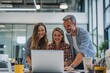© khalid_spk - Four colleagues gathered around a laptop in a modern office