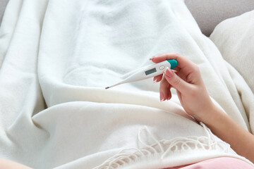 Wall Mural - Woman holding a digital thermometer. Concept of fever, flue, virus and quarantine 