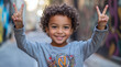© Marina Varnava - Joyful child with curly hair celebrating with peace signs in a vibrant urban alleyway