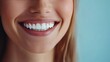 © Pricha.RT - A close-up shot of a woman's bright smile, featuring perfectly aligned white teeth, with a light blue background enhancing the image's clarity.