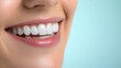 © Pricha.RT - A close-up shot of a woman's bright smile, featuring perfectly aligned white teeth, with a light blue background enhancing the image's clarity.