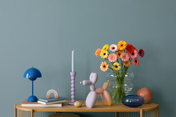 Wall Mural - A harmonious display of colorful flowers, pastel candle holders, and quirky modern decor on a wooden shelf, set against a teal wall.