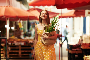 Wall Mural - With spring onion. Young woman is on the vegetable market or bazaar