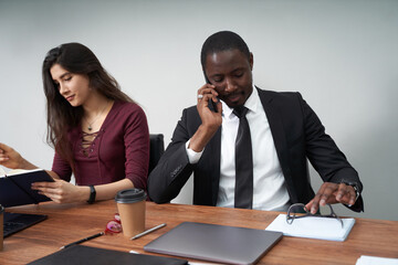 Wall Mural - Young happy business people working together in modern office, multiethnic teamwork. Man calling with smartphone