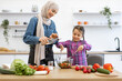 © sofiko14 - Muslim mother and daughter add olive oil to salad bowl. Family bonding while preparing fresh vegetable salad. Teaching cooking skills and healthy eating habits.