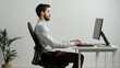 © Gatherina - Office worker sitting with correct posture at desk typing on keyboard
