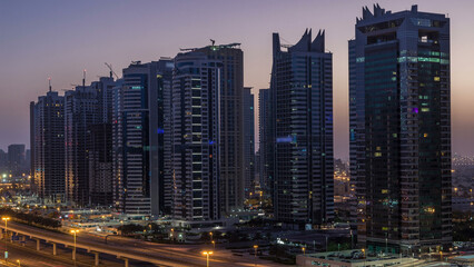 Poster - Aerial view of Jumeirah lakes towers skyscrapers night to day timelapse with traffic on sheikh zayed road.