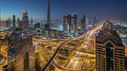 Dubai downtown skyline with tallest skyscrapers and busiest traffic on highway intersection night to day timelapse