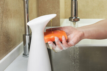 Wall Mural - Cropped image of woman holding washing sponge with dishwashing liquid over sink, cleaning concept