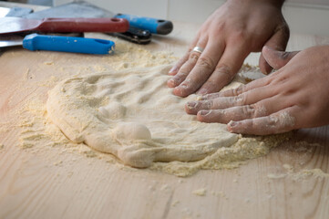 baker's hands knead the dough, form it for pizza, flour on the table