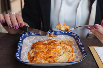 Cutting lasagna food on a plate in a close-up view.