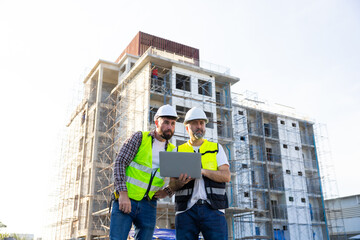 Wall Mural - Architect and contractor working on building in construction site. Two Professional Architects Engineer Working on Personal laptop computer at house construction site