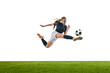 © Lustre Art Group  - Young woman, soccer player, mid-flight, aiming precise kick at ball, showcasing agility and focus on green stadium against white studio background. Concept of sport, competition, tournament, game