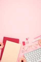 Wall Mural - Top view keyboard, glasses, paper notebooks, clips, supplies, flowers on pink background. Stylish feminine workspace.