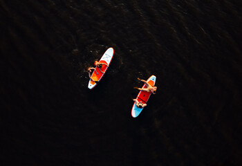 Wall Mural - Aerial view of friends on sup board enjoying a day at lake during sunset.