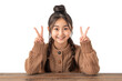© IMOTION - Confident Asian teenage girl showing something sitting at the table isolated on transparent background