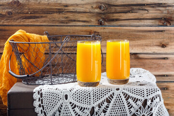 Fresh pumpkin and orange juice with sunflower branches on old wooden wall