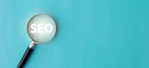 Wall Mural - close up top view on magnify glass with word seo (search engine optimization) on blue color backgrou