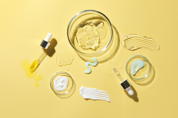 Wall Mural - Petri dishes with cosmetic products and pipettes on yellow background, flat lay