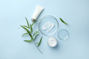 Poster - Petri dishes with cosmetic product and leaves on light blue background, flat lay