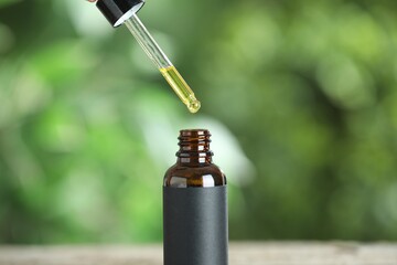 Poster - Dripping tincture from pipette into bottle against blurred green background, closeup