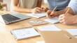 © Rona_65 - Collaborative workspace scene with hands writing notes, using a laptop, and organizing creative ideas on a wooden desk.