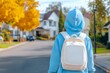 © Punprapa - A girl wearing a blue hoodie and white backpack is walking down the street, viewed from behind