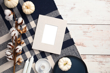 Wall Mural - Autumn flat lay composition with photo frame, plaid, cotton, pumpkins, candles on rustic wooden table.