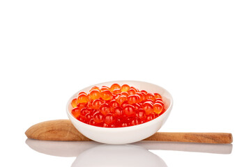 Red caviar in a ceramic plate with a spoon, macro, isolated on a white background