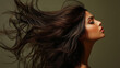 © Oksana - A profile of a young woman with dark loose hair blowing in the air, highlighting her refined look and elongated facial features on a neutral background