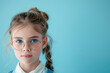 © Ирина Селина - Portrait of blue-eyed Caucasian schoolgirl 10 years old in glasses and school uniform with relaxed expression on light blue background with copy space on right