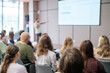 © Anton Gvozdikov - Blurry image of business presentation with audience seated in modern conference room, focusing on learning and collaboration