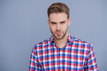 Stylish face portrait of unshaven guy. Man isolated on grey. Millennial man wearing checkered shirt. Casual style of millennial man. Portrait of young man in casual style shirt. Copy space