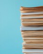 © ParinApril - A stack of neatly arranged papers showcasing various colors against a calming blue background, symbolizing organization and clarity.