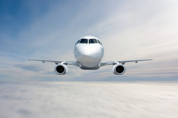 Wall Mural - Front view of the white passenger jet plane flies in the air above the clouds