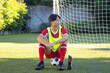 © Wavebreak Media - Resting on soccer field, athlete in uniform with soccer ball and water bottle