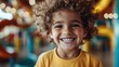 ©  Jovaduplex - A cheerful child with curly hair grins widely, set against a bright, lively background. The image captures the essence of childhood joy and the innocence of fun times.
