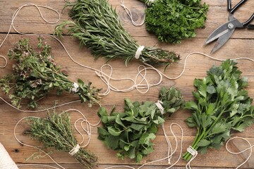 Sticker - Bunches of different aromatic herbs, rope and scissors on wooden table, flat lay