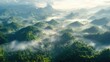 © sa-photo - An aerial view of a mountain range covered in dense forest, with mist rising from the valleys and peaks piercing through the clouds.