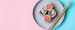 © Georgii - Top view of assorted sushi rolls on a round plate with pastel pink and blue background and chopsticks alongside