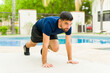 © AntonioDiaz - Young man doing mountain climber exercise poolside during a backyard workout session