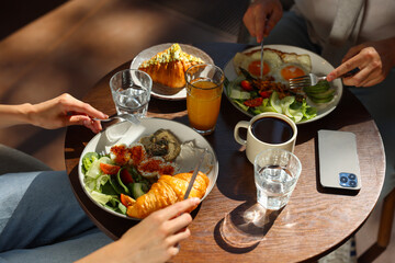 Canvas Print - Couple having tasty breakfast at wooden table in cafe, closeup