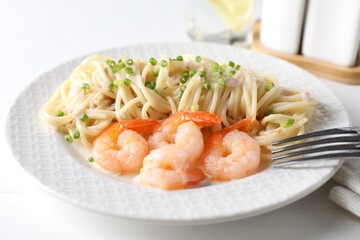 Delicious pasta with shrimps and green onions on white table, closeup