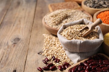 Canvas Print - Different types of cereals and legumes on wooden table, closeup. Space for text