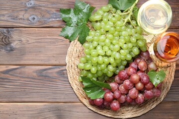 Canvas Print - Fresh ripe grapes and glasses of wine on wooden table, flat lay. Space for text