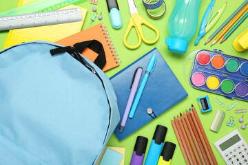 Wall Mural - Backpack and different school stationery on light green background, flat lay