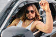 © SHOTPRIME STUDIO - Confident man with long hair holding car keys from window